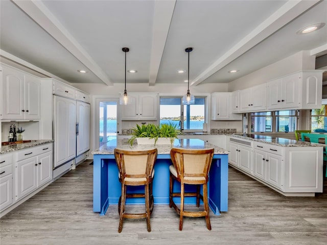 kitchen with a kitchen island, white cabinets, decorative light fixtures, and beamed ceiling