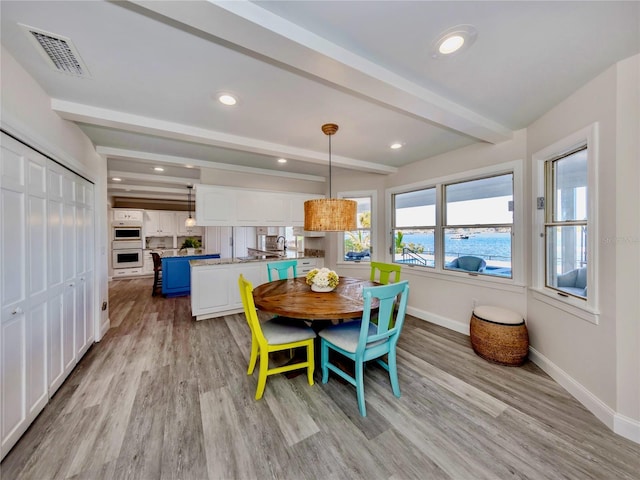 dining area featuring light hardwood / wood-style floors and beamed ceiling