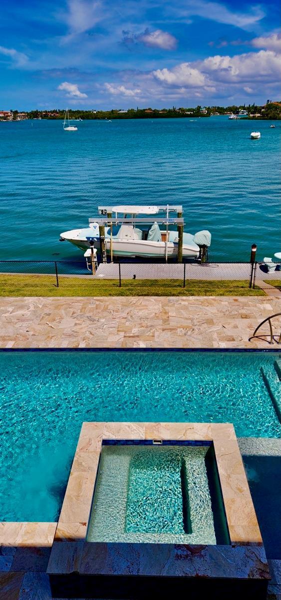 view of swimming pool featuring a water view and an in ground hot tub