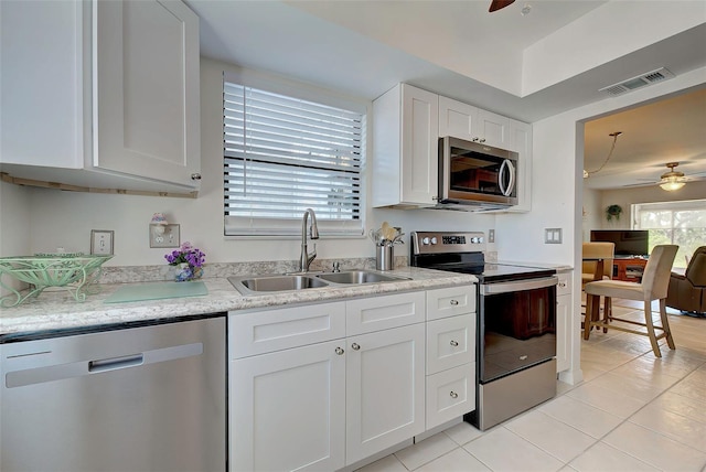 kitchen with ceiling fan, sink, stainless steel appliances, light tile patterned floors, and white cabinets