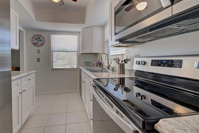 kitchen featuring sink, stainless steel appliances, light tile patterned floors, a raised ceiling, and white cabinets