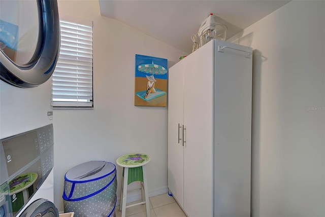 laundry room with stacked washer and clothes dryer and light tile patterned flooring