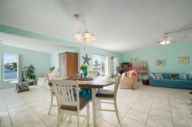 tiled dining room with ceiling fan with notable chandelier and a textured ceiling