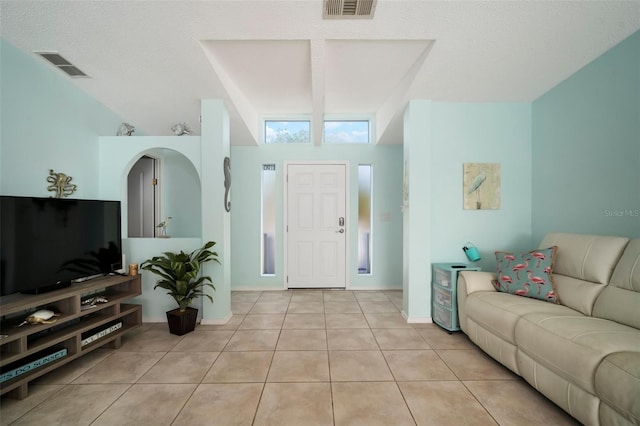 living room featuring light tile patterned floors, a textured ceiling, and a towering ceiling