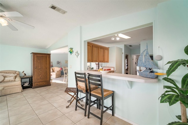 kitchen featuring kitchen peninsula, a kitchen breakfast bar, light tile patterned floors, and ceiling fan