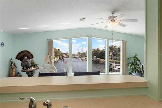 room details with ceiling fan, a water view, and a textured ceiling