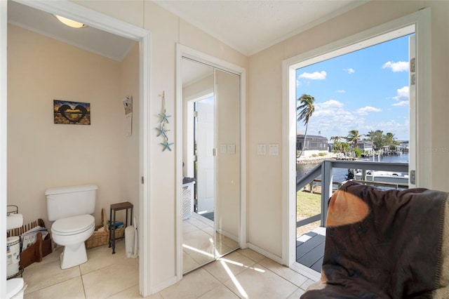 interior space featuring toilet, a water view, tile patterned floors, and ornamental molding