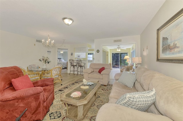 living room with ceiling fan with notable chandelier and light wood-type flooring