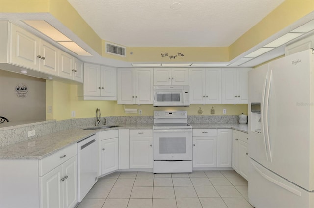 kitchen with white appliances, sink, light stone countertops, light tile patterned floors, and white cabinetry