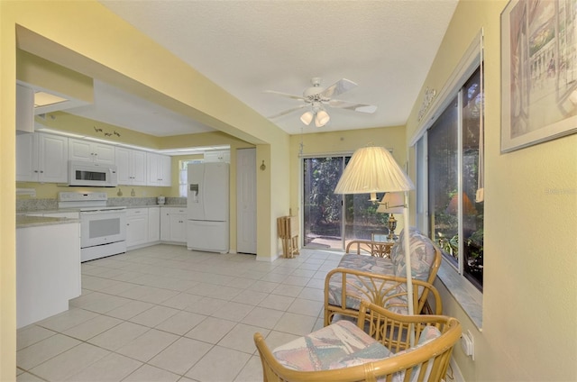 kitchen with white appliances, white cabinets, ceiling fan, light tile patterned floors, and a textured ceiling