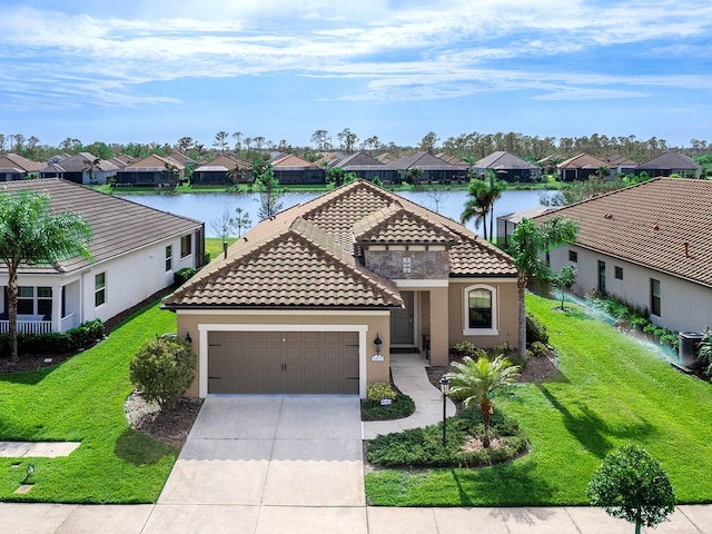 mediterranean / spanish home with a front yard, a water view, and a garage