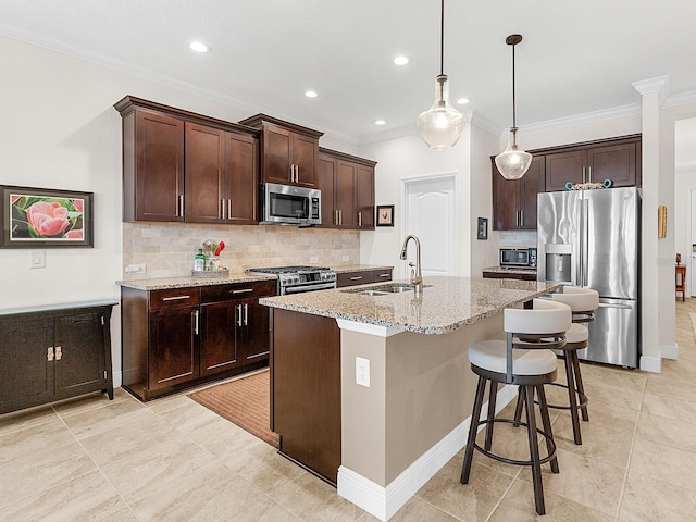 kitchen featuring sink, light stone counters, dark brown cabinets, a center island with sink, and appliances with stainless steel finishes