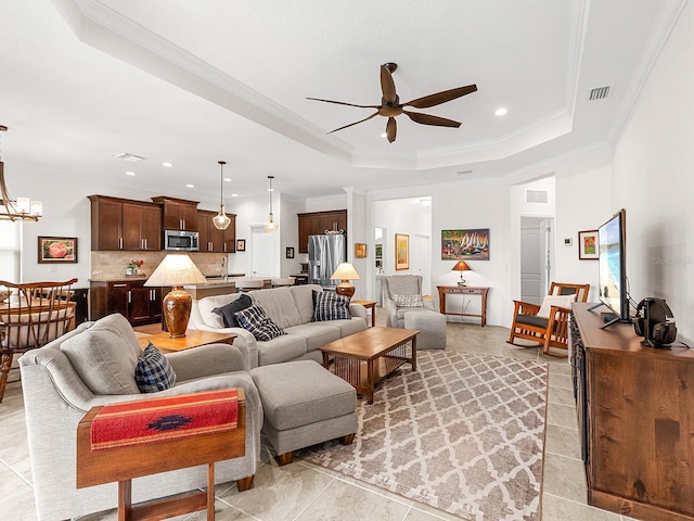 living room with ceiling fan with notable chandelier, a raised ceiling, crown molding, and sink