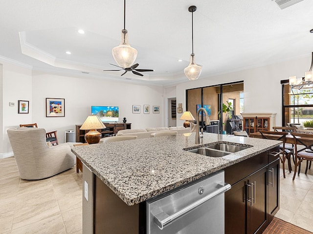 kitchen with ceiling fan, sink, a raised ceiling, stainless steel dishwasher, and an island with sink