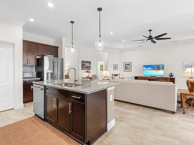 kitchen featuring appliances with stainless steel finishes, light stone counters, dark brown cabinets, sink, and an island with sink