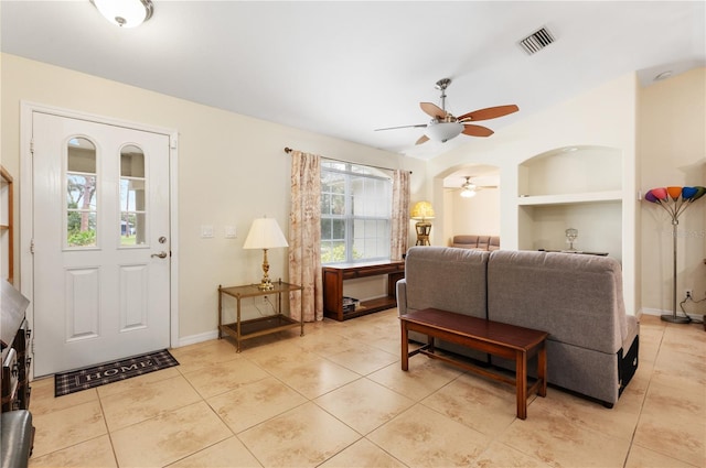 living room with built in shelves, ceiling fan, and light tile patterned floors