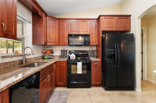 kitchen featuring lofted ceiling, black appliances, sink, light stone countertops, and light tile patterned floors