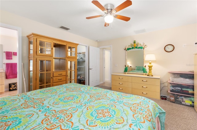 carpeted bedroom featuring a walk in closet, ensuite bathroom, a closet, and ceiling fan