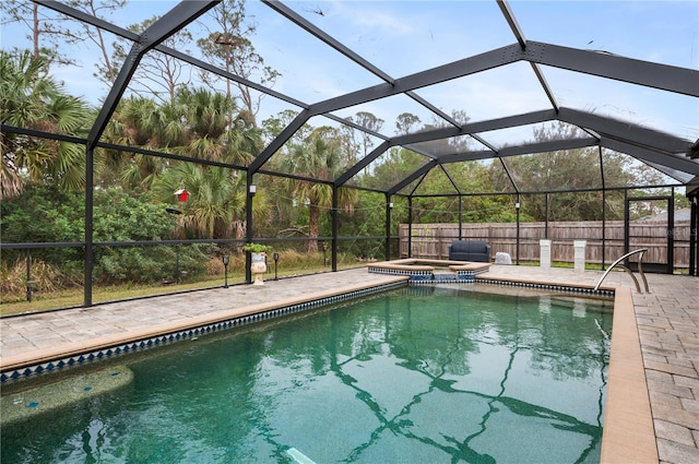 view of pool featuring glass enclosure, an in ground hot tub, and a patio area