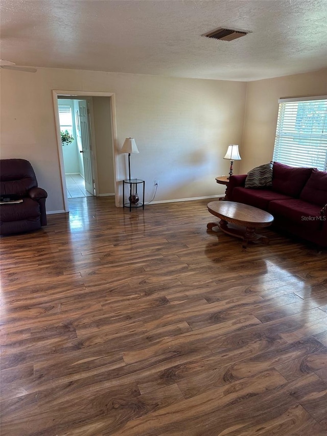 living room with a textured ceiling and dark wood-type flooring