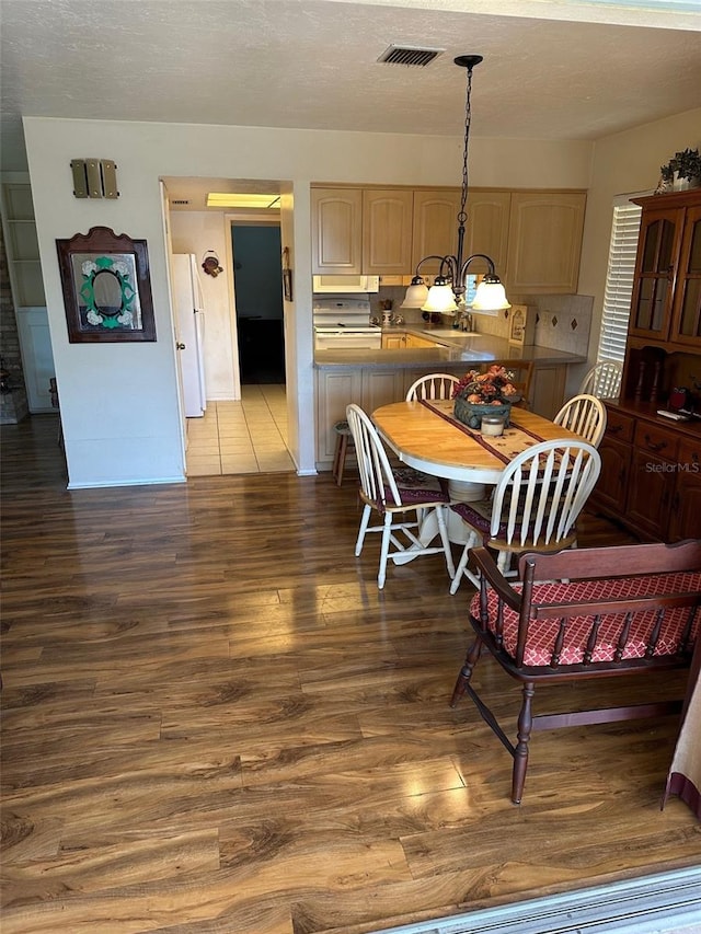 dining area featuring dark wood-type flooring and an inviting chandelier