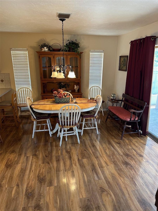 dining room with a textured ceiling, dark hardwood / wood-style floors, and an inviting chandelier