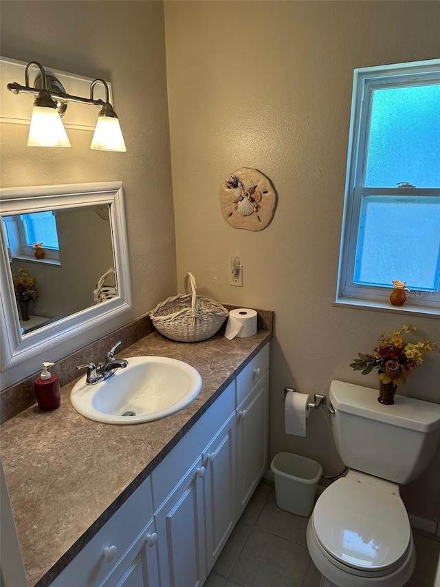 bathroom with toilet, vanity, and tile patterned floors