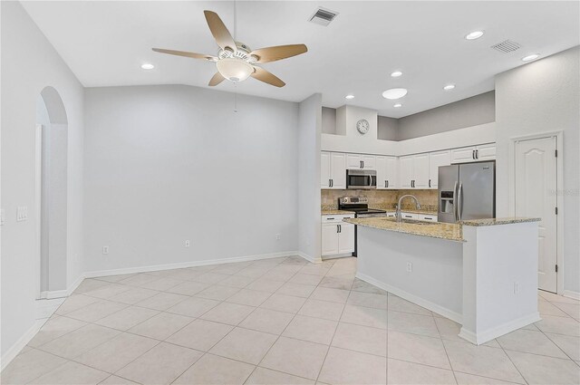 4575 Cancello Grande Ave, Venice, FL 34293 - kitchen with light stone counters, light tile patterned floors, an island with sink, stainless steel appliances, and white cabinets