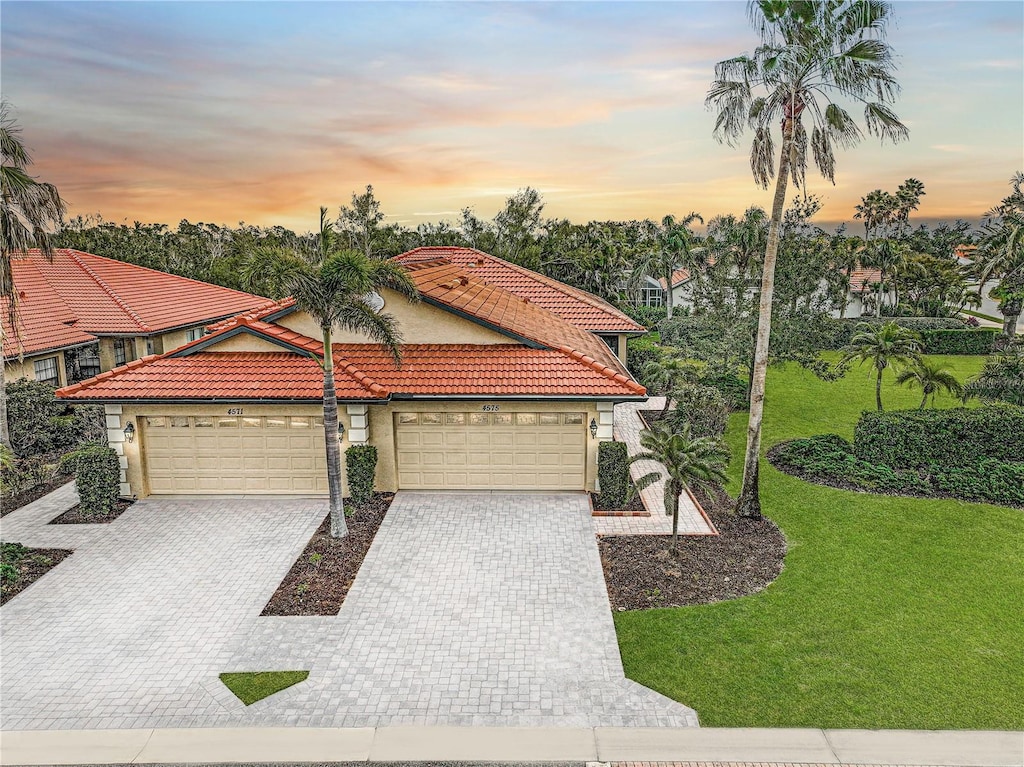 mediterranean / spanish-style home with a garage and a lawn