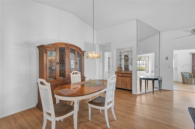 dining area featuring light hardwood / wood-style floors, high vaulted ceiling, and ceiling fan with notable chandelier