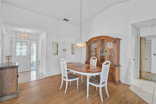 dining room featuring light wood-type flooring and vaulted ceiling