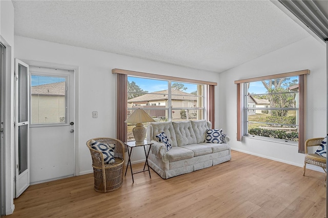 sitting room featuring lofted ceiling, a textured ceiling, and light hardwood / wood-style flooring