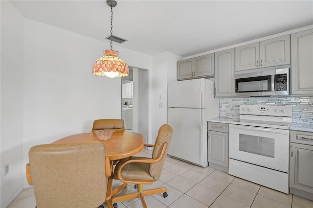 kitchen featuring pendant lighting, white appliances, gray cabinets, and washer / clothes dryer