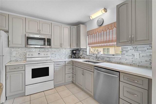 kitchen featuring light tile patterned floors, gray cabinets, appliances with stainless steel finishes, tasteful backsplash, and sink