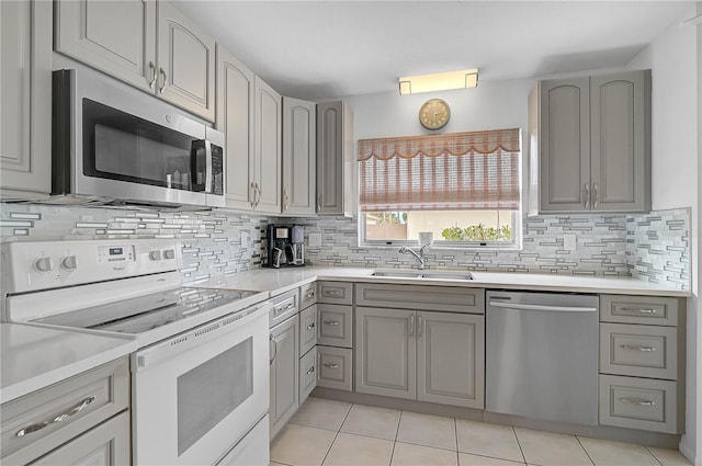 kitchen featuring light tile patterned flooring, appliances with stainless steel finishes, gray cabinetry, and sink