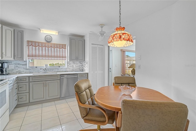 kitchen featuring stainless steel dishwasher, decorative backsplash, sink, light tile patterned floors, and gray cabinetry