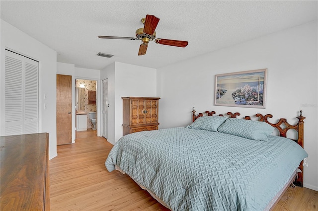 bedroom with ceiling fan, light wood-type flooring, connected bathroom, a textured ceiling, and a closet