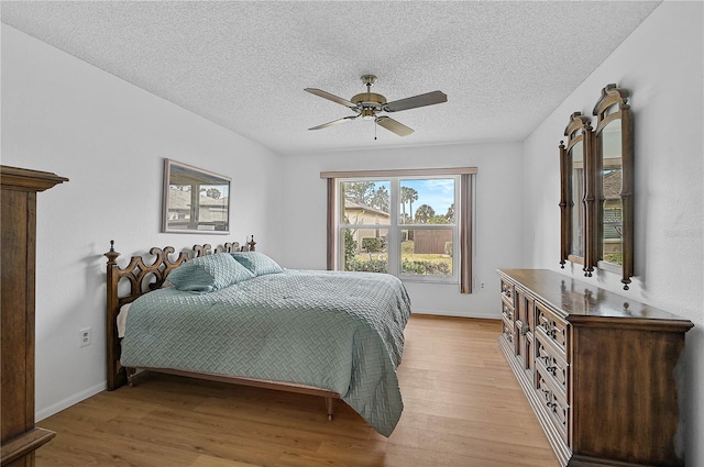 bedroom featuring light wood-type flooring, ceiling fan, and a textured ceiling