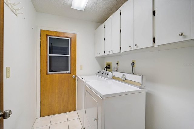 laundry area with a textured ceiling, cabinets, light tile patterned flooring, and separate washer and dryer