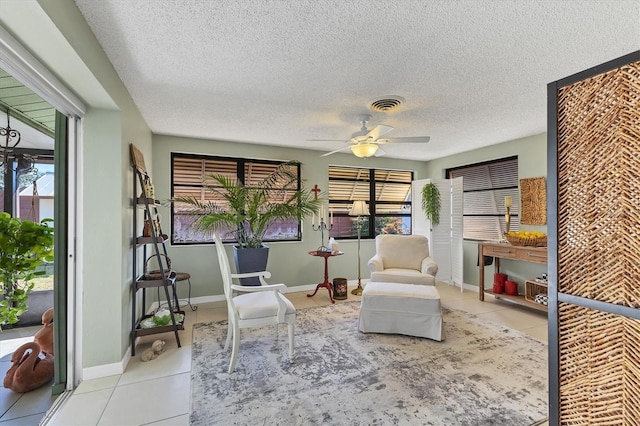 living area with a healthy amount of sunlight, light tile patterned floors, and ceiling fan