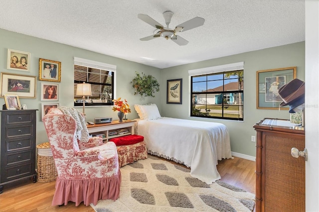 bedroom featuring ceiling fan, a textured ceiling, and light wood-type flooring