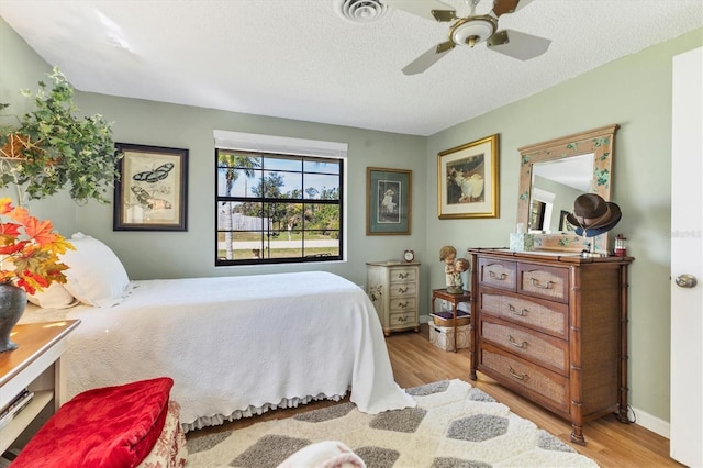 bedroom featuring ceiling fan, light hardwood / wood-style flooring, and a textured ceiling