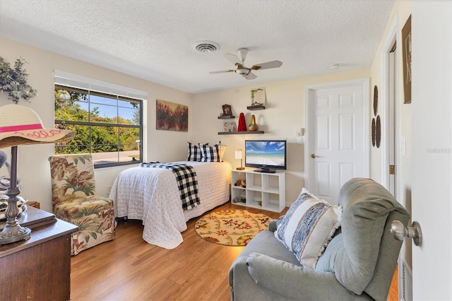 bedroom with hardwood / wood-style flooring, a textured ceiling, and ceiling fan