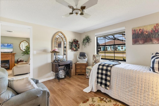 bedroom with ceiling fan, light hardwood / wood-style floors, and a textured ceiling