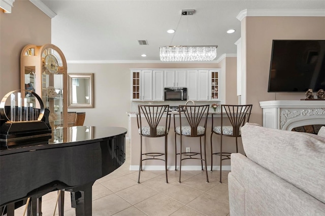 interior space with ornamental molding, light tile patterned floors, decorative light fixtures, white cabinetry, and a chandelier