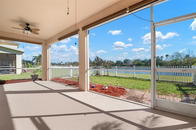 unfurnished sunroom with a water view and ceiling fan