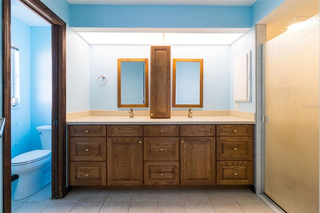 bathroom with tile patterned flooring, vanity, a shower with shower door, and toilet