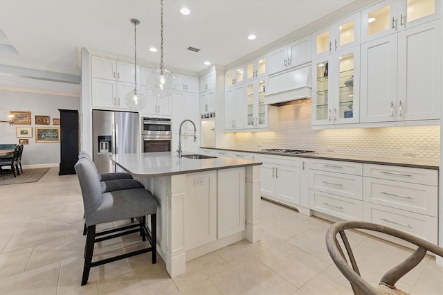 kitchen featuring pendant lighting, white cabinetry, stainless steel appliances, sink, and a center island with sink