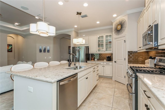 kitchen with stainless steel appliances, an island with sink, decorative backsplash, sink, and hanging light fixtures