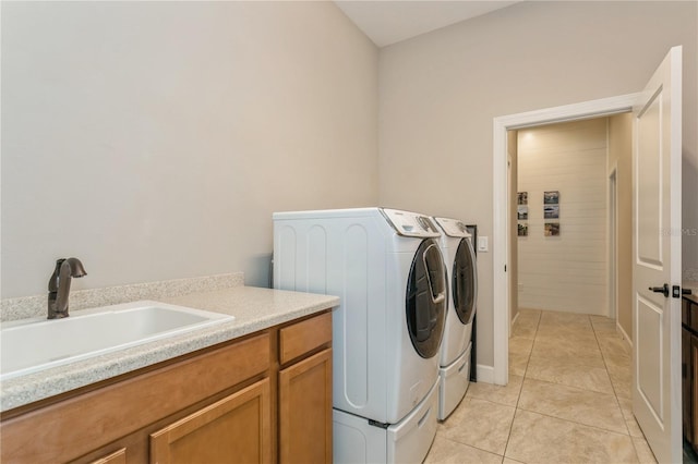 laundry area with cabinets, sink, light tile patterned floors, and washing machine and clothes dryer